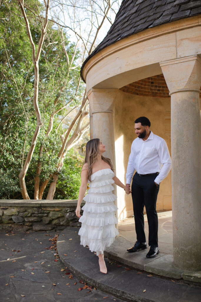 Man and woman hold hands and walk together in front of the rotunda at Graylyn Estate.