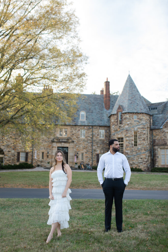 Man and woman stand a few steps apart from one another looking in opposite directions in front of Graylyn Estate.