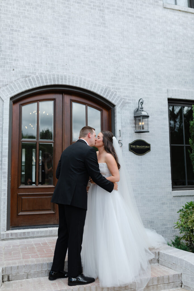 The bride and groom share a kiss on the steps outside the front of The Bradford.